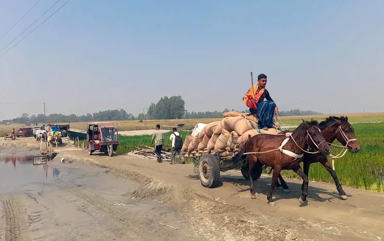 কাঁচা সড়কে ঘোড়ার গাড়িতে পণ্য পরিবহন করছেন এক ব্যক্তি